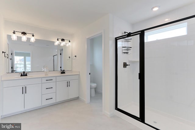 bathroom with vanity, toilet, a shower with door, and a healthy amount of sunlight