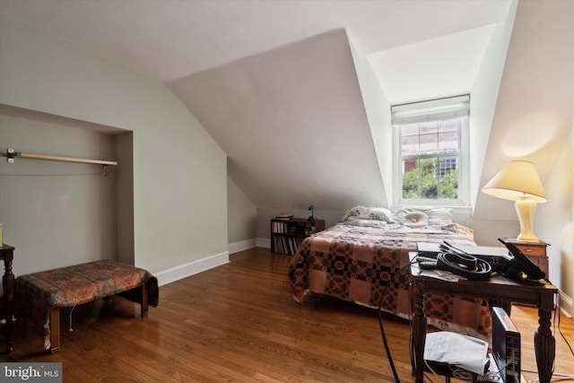 bedroom featuring baseboards, lofted ceiling, and wood finished floors