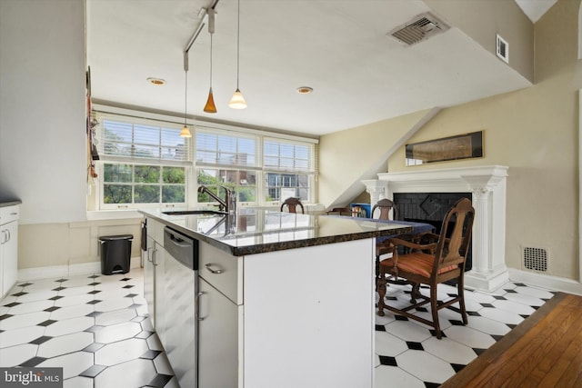 kitchen with a sink, visible vents, an island with sink, and dishwasher