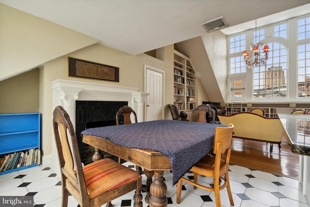 dining space featuring tile patterned floors, visible vents, a notable chandelier, and built in features