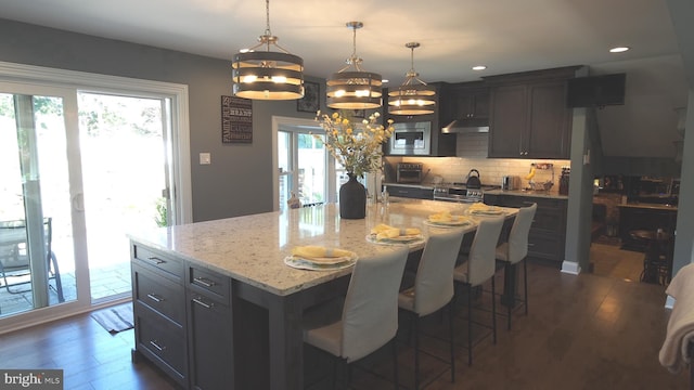 kitchen featuring a center island with sink, dark hardwood / wood-style floors, and plenty of natural light