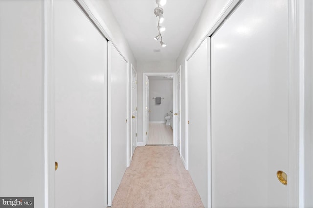 hallway with light carpet and track lighting