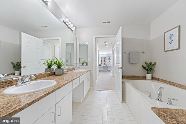 bathroom featuring vanity, tile patterned floors, and a relaxing tiled tub