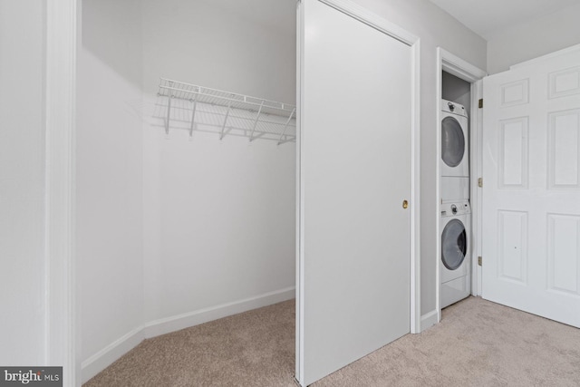 laundry room with light carpet and stacked washer and dryer