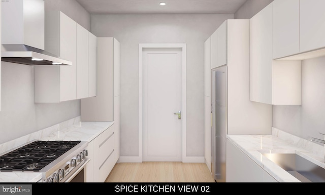 kitchen featuring white cabinetry, wall chimney exhaust hood, light hardwood / wood-style flooring, and stainless steel range