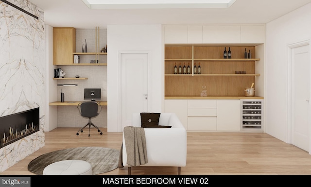 office space with wine cooler, built in desk, and light wood-type flooring