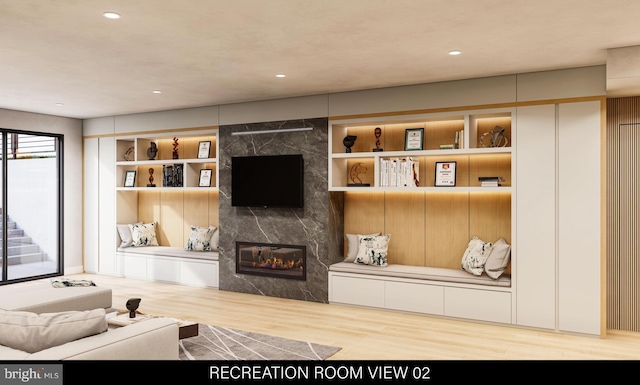 living area with recessed lighting, built in features, wood finished floors, and a premium fireplace
