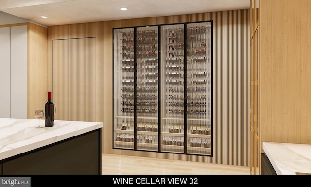 wine room with light hardwood / wood-style flooring and wood walls