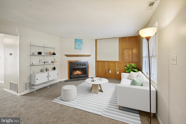 living room with a textured ceiling, a tiled fireplace, and carpet flooring