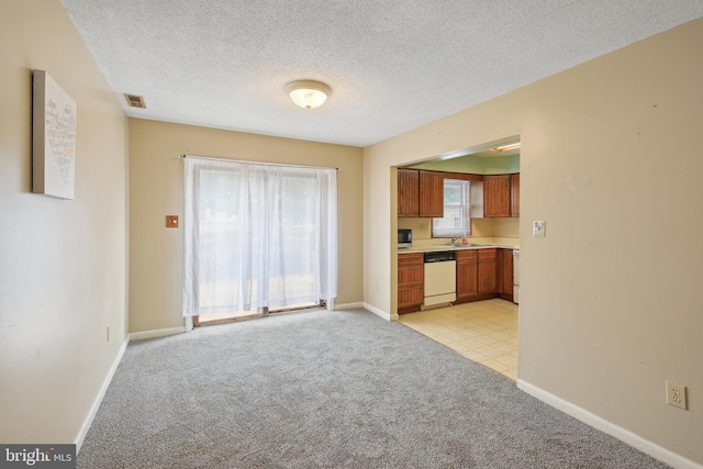 kitchen featuring a textured ceiling, sink, white dishwasher, and light colored carpet