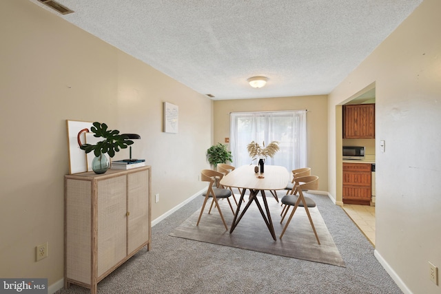 carpeted dining room with a textured ceiling