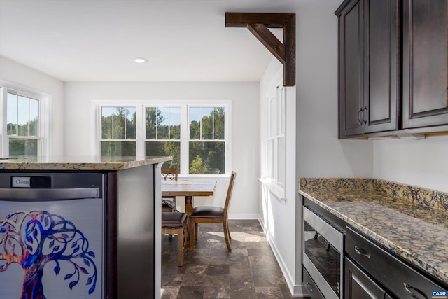 kitchen featuring dark stone countertops, appliances with stainless steel finishes, and dark brown cabinetry