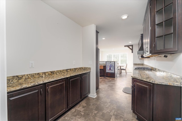 kitchen with stainless steel gas cooktop, light stone counters, and dark brown cabinets