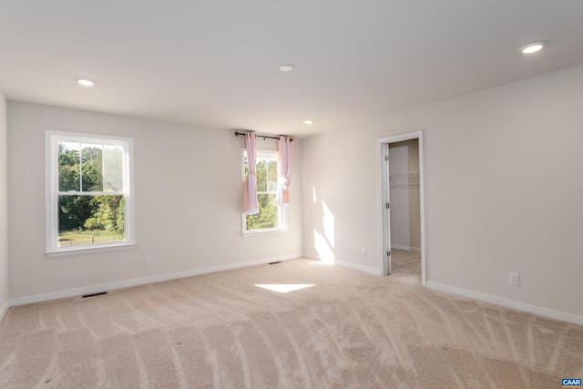 unfurnished room featuring plenty of natural light and light carpet