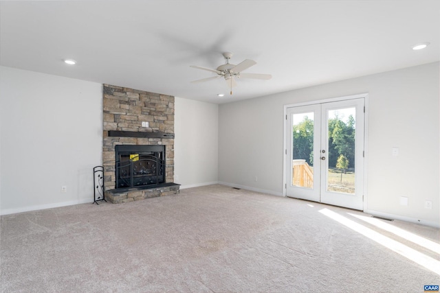 unfurnished living room with a fireplace, french doors, light colored carpet, and ceiling fan