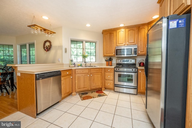 kitchen featuring a textured ceiling, sink, kitchen peninsula, stainless steel appliances, and light tile patterned floors