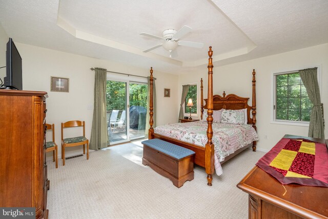 carpeted bedroom featuring access to outside, a textured ceiling, a raised ceiling, and ceiling fan