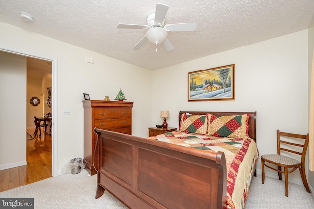 bedroom with light wood-type flooring, a textured ceiling, and ceiling fan