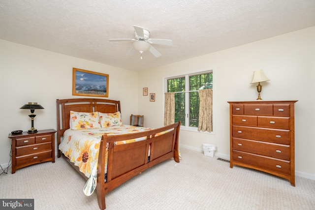 bedroom featuring light carpet, ceiling fan, and a textured ceiling