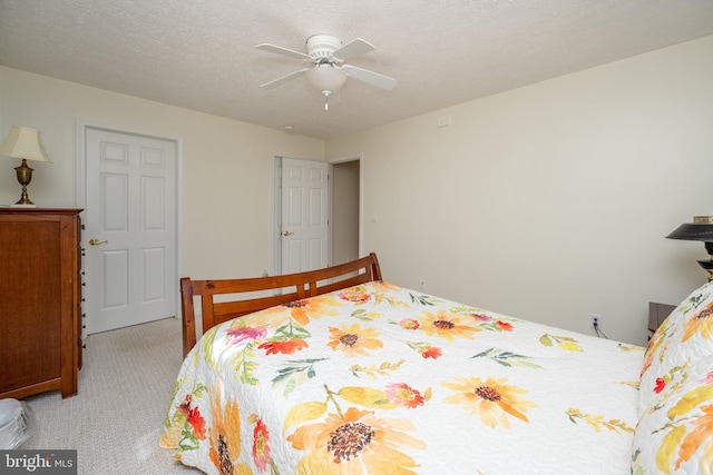 bedroom with ceiling fan, a textured ceiling, and light carpet