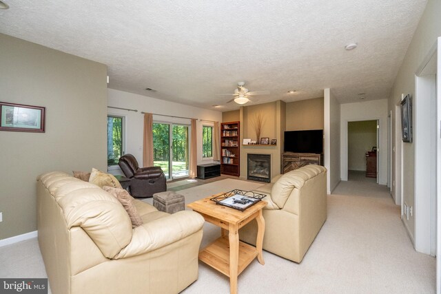 living room featuring ceiling fan, light colored carpet, and a textured ceiling