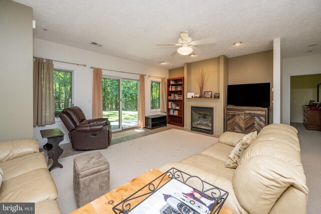 carpeted living room with a textured ceiling and ceiling fan