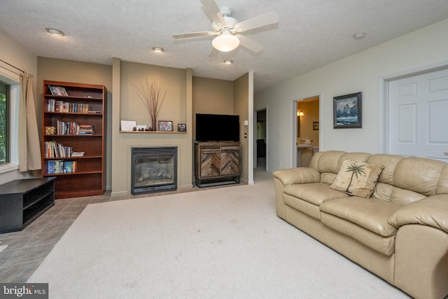 carpeted living room with ceiling fan and a textured ceiling