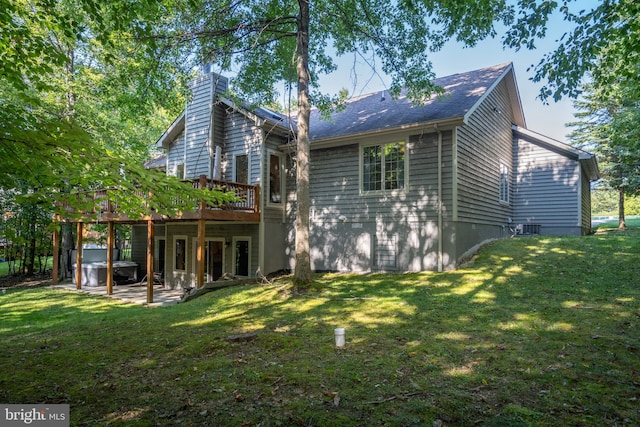 rear view of property with cooling unit, a wooden deck, a lawn, and a patio area