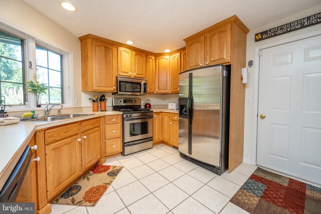 kitchen featuring appliances with stainless steel finishes, light tile patterned flooring, and sink