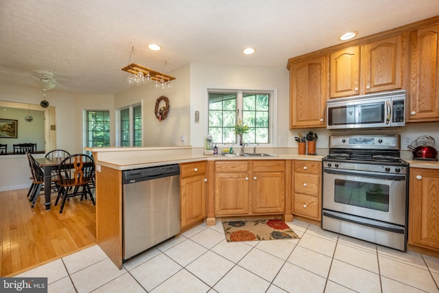 kitchen with light hardwood / wood-style floors, kitchen peninsula, stainless steel appliances, a textured ceiling, and sink