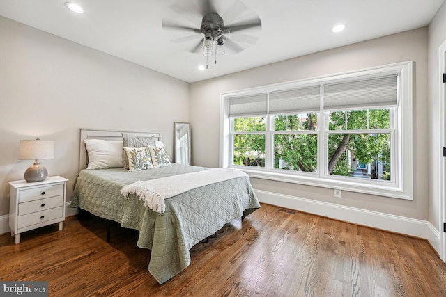 bedroom with multiple windows, dark hardwood / wood-style flooring, and ceiling fan