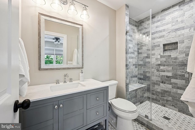 bathroom featuring ceiling fan, a shower with door, vanity, and toilet