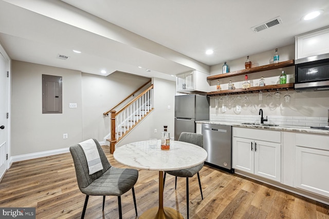 kitchen with light hardwood / wood-style floors, light stone countertops, stainless steel appliances, and white cabinets