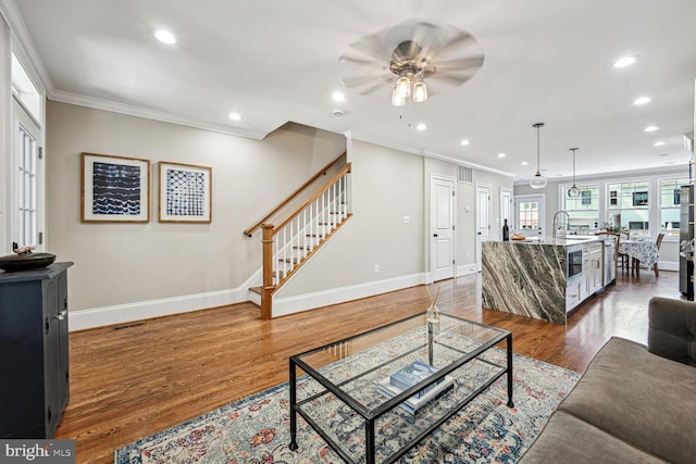 living room with ornamental molding, dark hardwood / wood-style flooring, ceiling fan, and sink