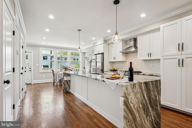 kitchen with white cabinetry, light stone counters, dark hardwood / wood-style flooring, sink, and wall chimney range hood