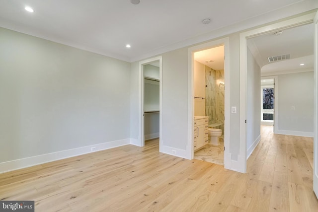 unfurnished bedroom featuring a walk in closet, light wood-type flooring, a closet, and ensuite bath