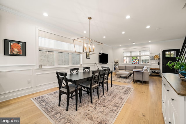 dining space with light hardwood / wood-style flooring, a chandelier, and ornamental molding