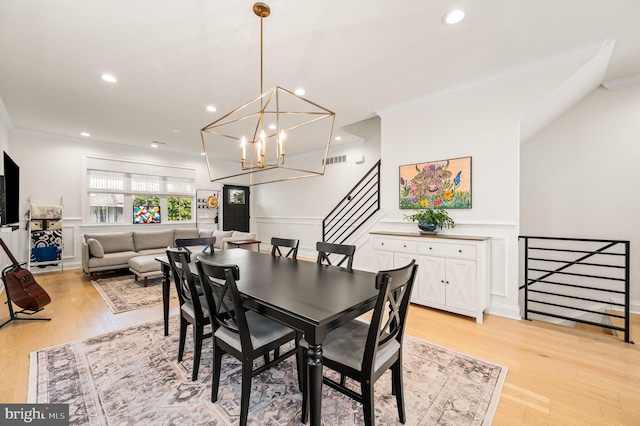 dining area with an inviting chandelier, light wood-type flooring, and ornamental molding