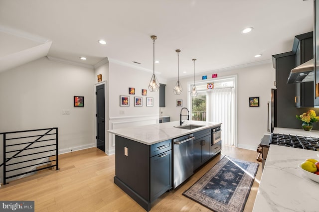 kitchen with appliances with stainless steel finishes, an island with sink, light stone countertops, decorative light fixtures, and sink