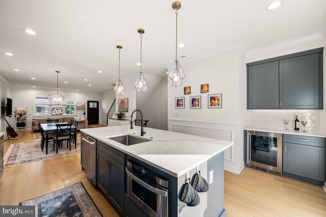 kitchen with beverage cooler, a center island with sink, light wood-type flooring, and sink