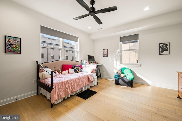 bedroom with ceiling fan, light hardwood / wood-style floors, and multiple windows