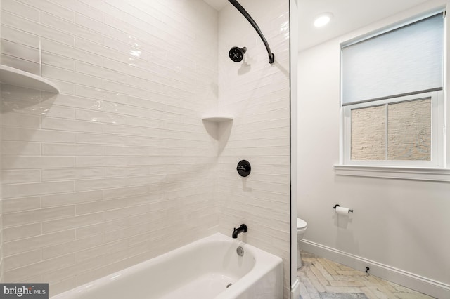 bathroom featuring plenty of natural light, toilet, and tiled shower / bath