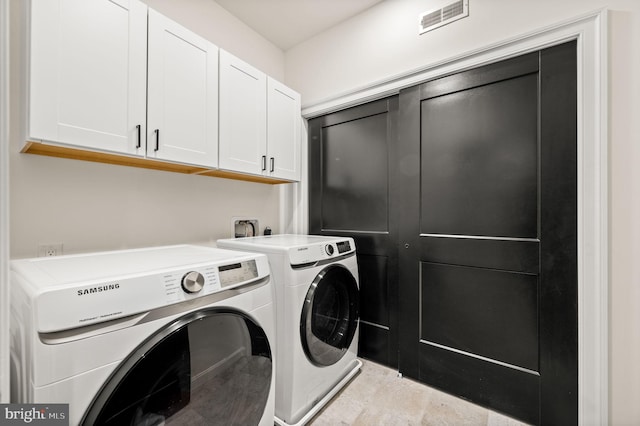 washroom featuring washing machine and clothes dryer and cabinets