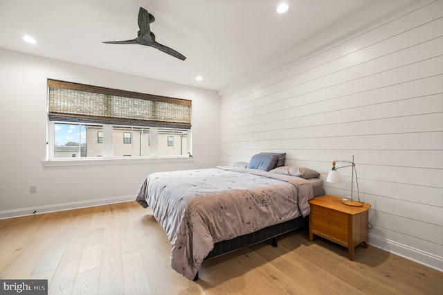 bedroom featuring wooden walls, light hardwood / wood-style floors, and ceiling fan