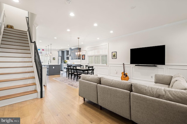 living room with crown molding, light hardwood / wood-style floors, and a chandelier