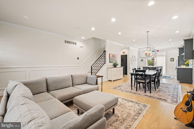 living room featuring a chandelier, light hardwood / wood-style floors, and crown molding