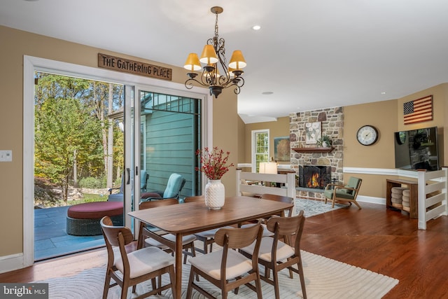 dining space featuring a notable chandelier, a fireplace, and hardwood / wood-style floors