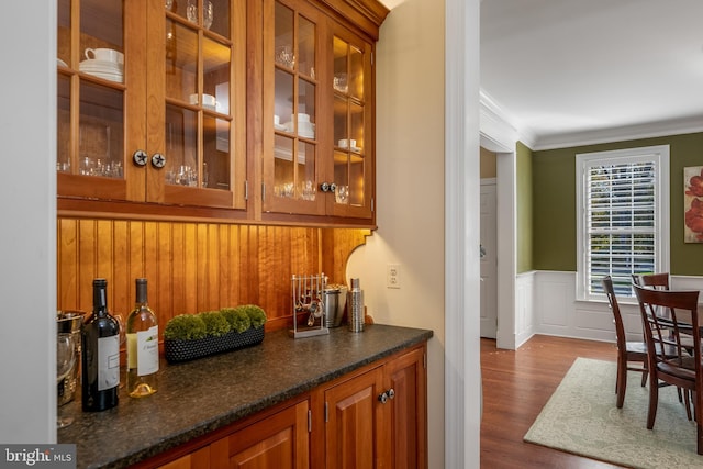 bar featuring crown molding, hardwood / wood-style floors, and dark stone countertops