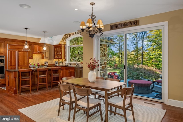 dining space with dark hardwood / wood-style floors, a healthy amount of sunlight, a chandelier, and sink