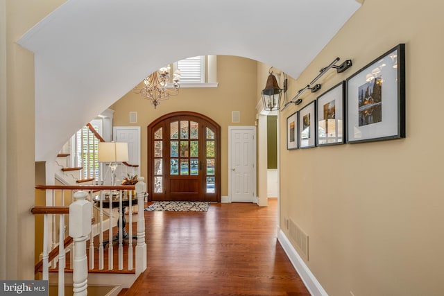 foyer with a notable chandelier, wood-type flooring, and a high ceiling